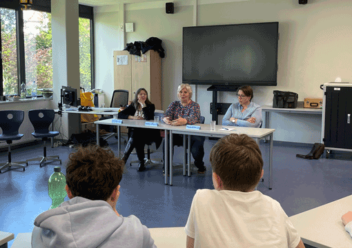 Zu sehen sind die Schulklasse und die Politikerinnen im Gespräch